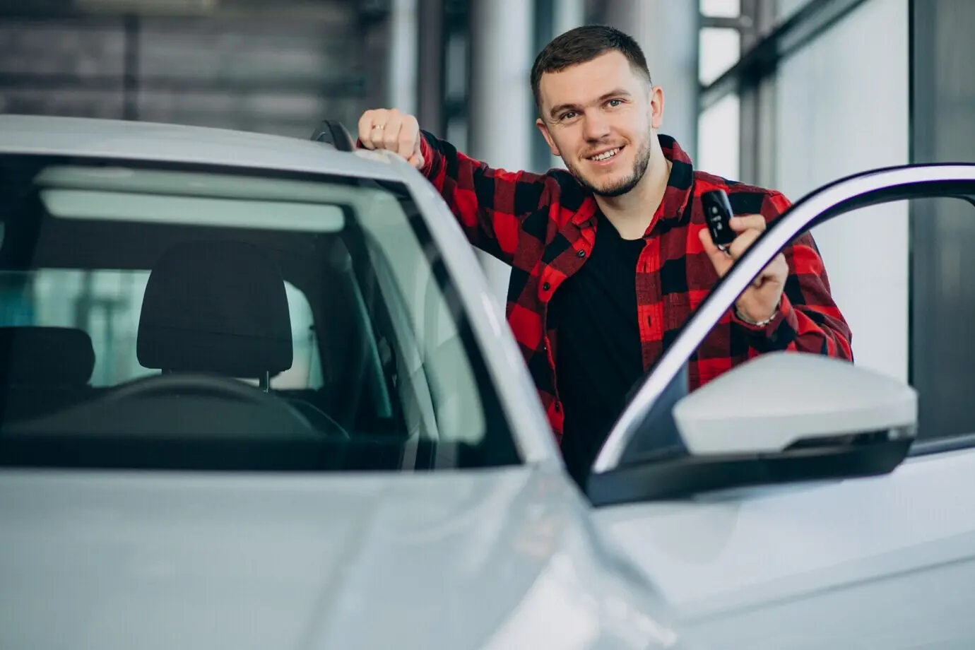 V autosalonu si mladý muž vybírá auto.